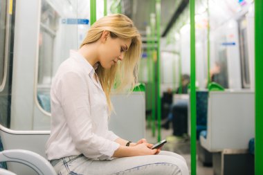 Genç kadın Londra metro tren akıllı telefon yazarak