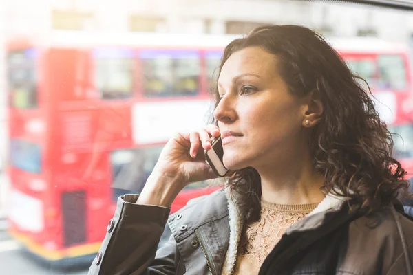 Beautiful woman typing on smart phone while commuting in London — Stock Photo, Image