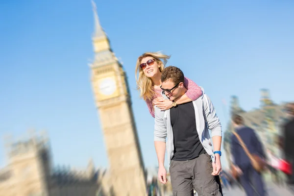 Gelukkige jonge paar genieten van een piggyback rijden in Londen — Stockfoto