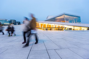 Alacakaranlıkta bulanık insanların Oslo Opera Binası önünde.