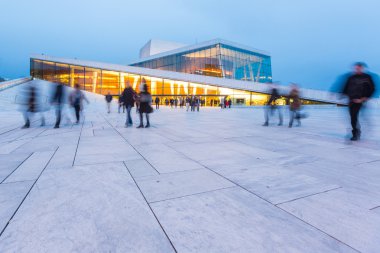 Alacakaranlıkta bulanık insanların Oslo Opera Binası önünde.