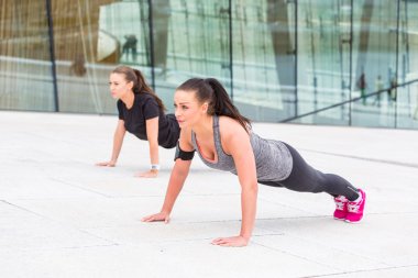 Two women doing push-ups exercises clipart