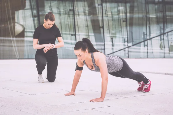 Vrouw doen push-ups oefeningen met haar personal trainer — Stockfoto