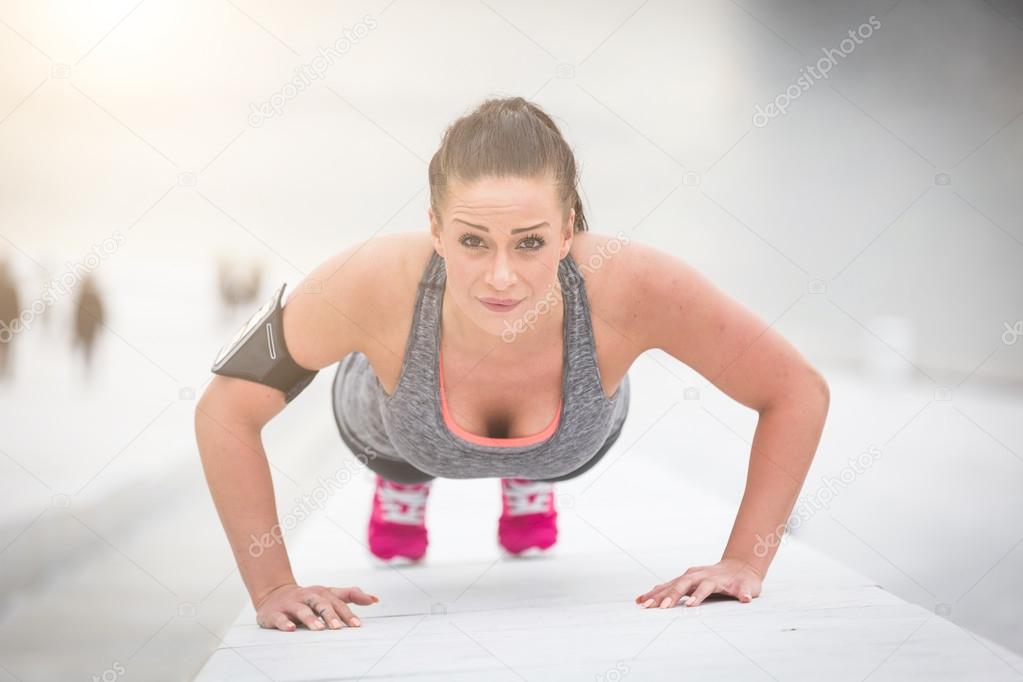 Young woman doing push-ups exercises