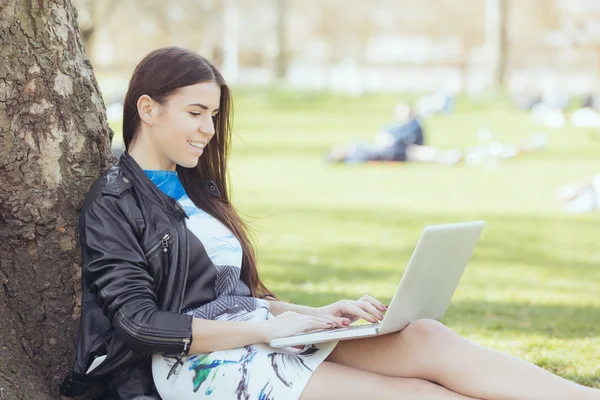 Jonge vrouw met behulp van computer op park in Londen — Stockfoto