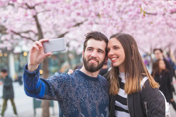 Hipster ζευγάρι που αναλαμβάνει ένα selfie στη Στοκχόλμη με άνθη κερασιάς — Φωτογραφία Αρχείου