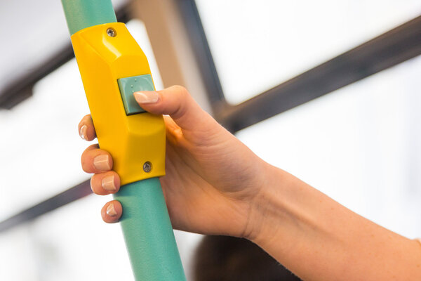 Молодая женщина нажимает кнопку стоп-запроса в автобусе
