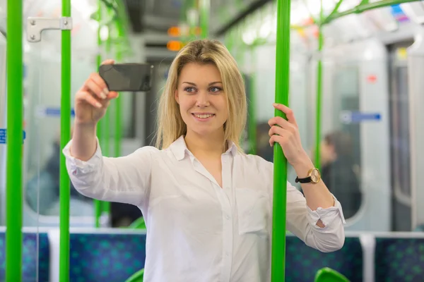 Молодая женщина делает селфи в поезде лондонского метро — стоковое фото