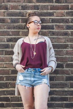 Hipster kadın portre Londra'da bir tuğla duvara.