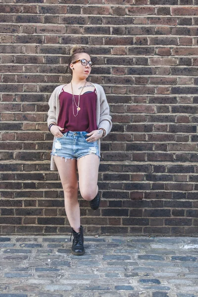Hipster kadın portre Londra'da bir tuğla duvara.