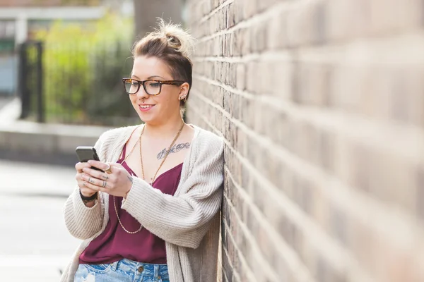 Hipster kobieta wpisując na inteligentny telefon w Londynie. — Zdjęcie stockowe