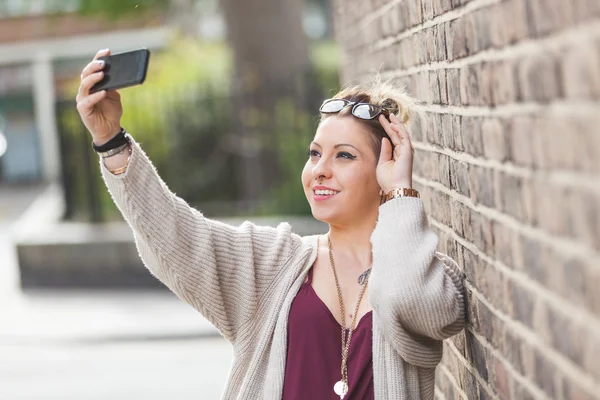 Hipster kobieta przy selfie przeciwko cegła na ścianie w Londynie. — Zdjęcie stockowe