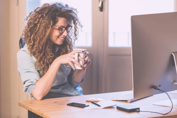 Ung kvinna som arbetar hemma eller på ett litet kontor — Stockfoto