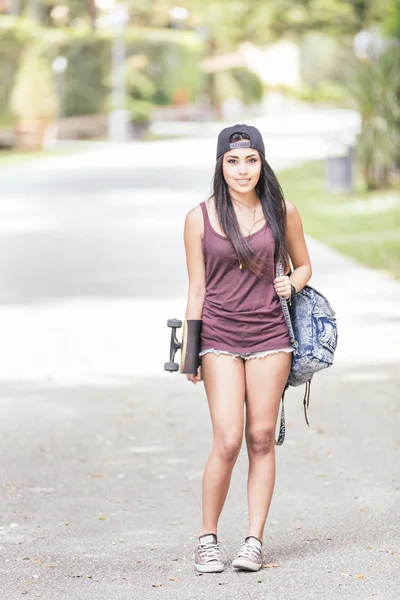 Menina bonita andando no parque segurando um skate . — Fotografia de Stock