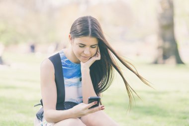 Genç kadın Parkı Londra'nın akıllı telefon bakarak