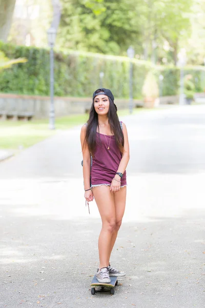 Hermosa chica de raza mixta patinando en el parque — Foto de Stock