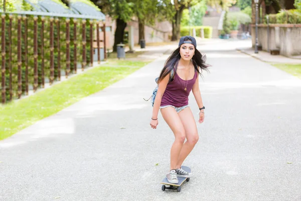 Hermosa chica de raza mixta patinando en el parque —  Fotos de Stock