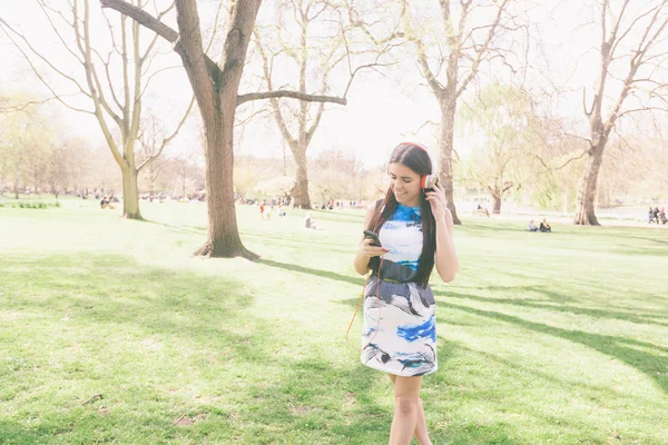 Junge Frau hört Musik im Park in London — Stockfoto