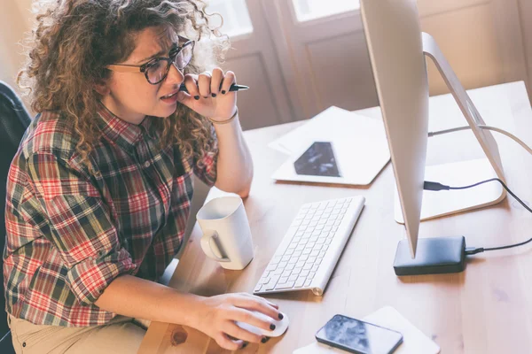 Mujer joven que trabaja en casa o en una pequeña oficina — Foto de Stock