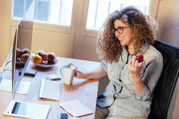 Junge Frau, die zu Hause oder in einem kleinen Büro arbeitet — Stockfoto