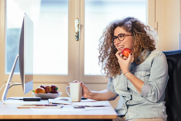 Junge Frau, die zu Hause oder in einem kleinen Büro arbeitet — Stockfoto