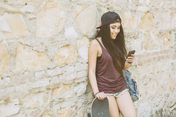 Portret van een mooie schaatser meisje op zoek naar slimme telefoon — Stockfoto