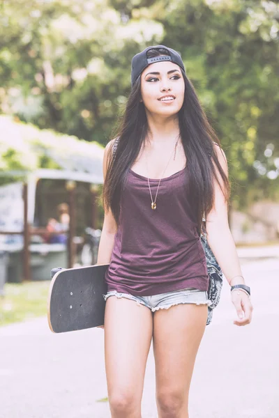 Vacker flicka gå på park håller en skateboard. — Stockfoto