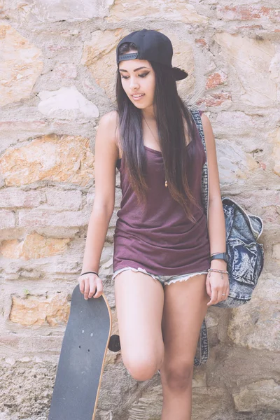 Retrato de uma bela garota patinadora contra a parede de pedra — Fotografia de Stock