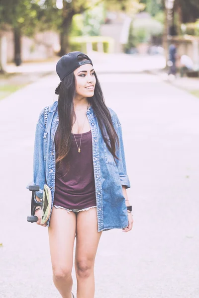 Menina bonita andando no parque segurando um skate . — Fotografia de Stock