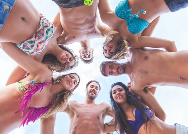 Multiracial group of friends embraced at seaside, bottom view. — Stock Photo, Image