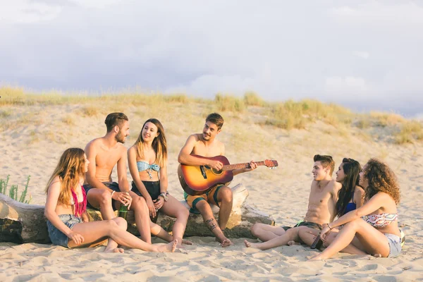 Groupe d'amis chantant sur la plage au coucher du soleil . — Photo