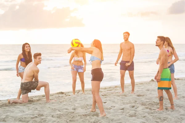 Группа друзей, играющих с мячом на пляже — стоковое фото