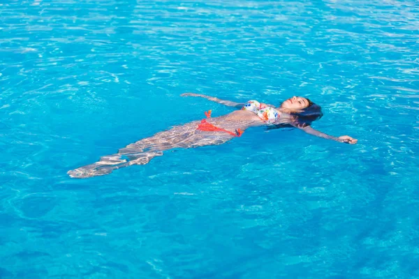 Bella donna sdraiata sulla superficie dell'acqua della piscina — Foto Stock