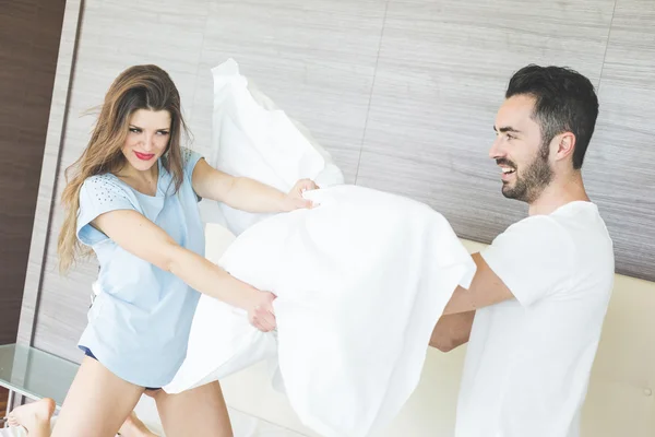 Couple heureux ayant la bataille d'oreiller dans la chambre d'hôtel — Photo