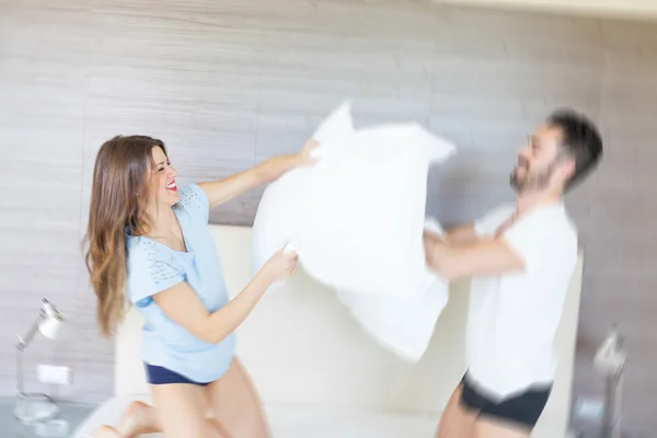 Casal feliz tendo travesseiro luta no quarto do hotel — Fotografia de Stock