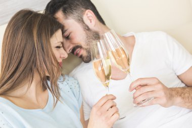 Happy couple making a toast on the bed