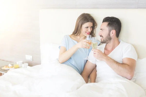 Casal feliz fazendo um brinde na cama — Fotografia de Stock