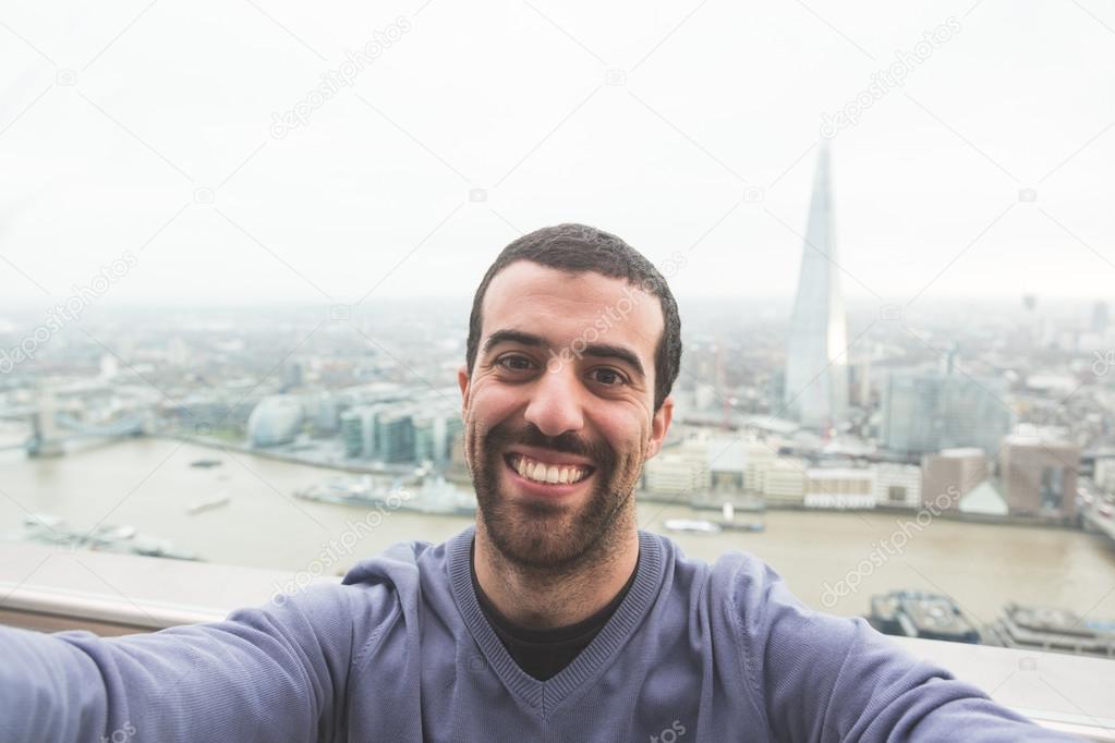 Young man taking a selfie with London cityscape on background