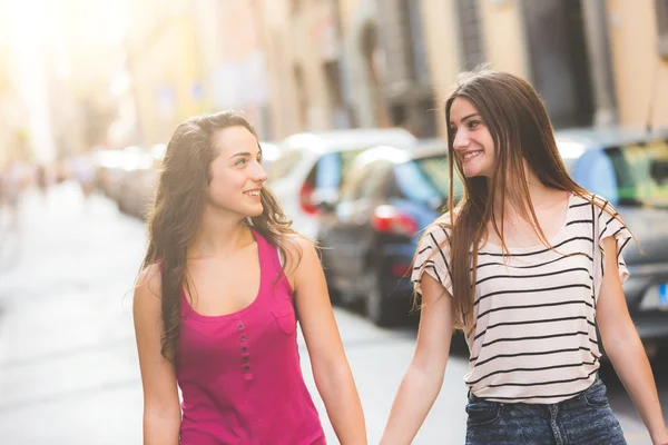 Zwei Mädchen, die Händchen haltend auf der Straße gehen — Stockfoto