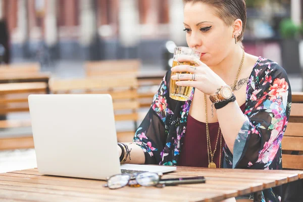 Chica trabajando en su computadora y bebiendo cerveza — Foto de Stock