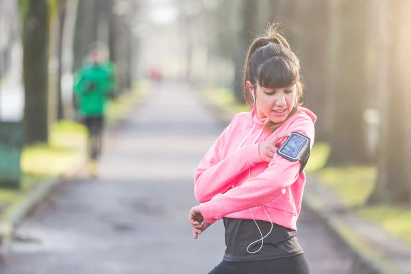 Unga sportiga kvinnan kontrollera smart telefon under träning — Stockfoto