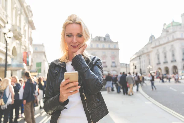 Volwassen vrouw kijken naar slimme telefoon in Londen — Stockfoto