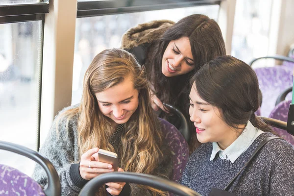 Drei Frauen, die im Bus ein Smartphone suchen — Stockfoto