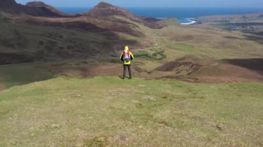 İskoçya 'daki Skye Adası' nı ve İskoçya 'daki Highlands' ı gezen maceraperest bir adam sarı ceketli bir adam bulutlu bir günde İskoçya 'da yürüyor ve eğleniyor.