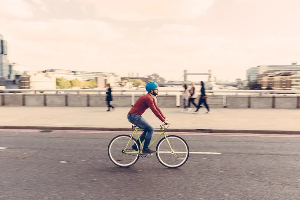 Человек-хипстер на велосипеде по Лондонскому мосту со стационарной экипировкой — стоковое фото