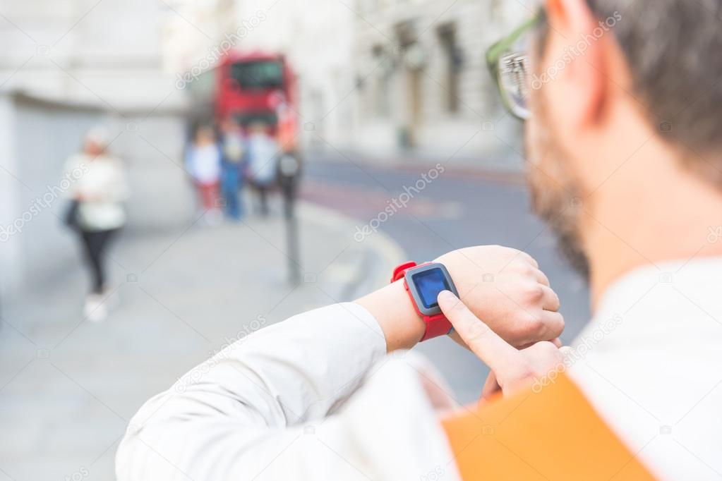 Male commuter in London looking at his smart watch