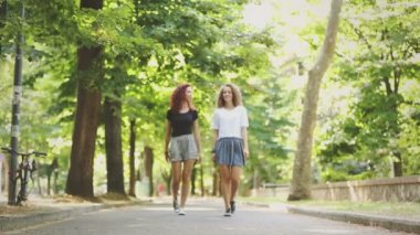 İki güzel kız tutuşup Park'ta yürümek