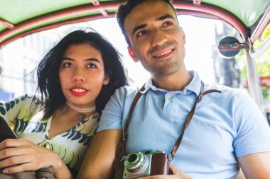 Tuk-tuk 'ta seyahat eden mutlu genç çift, yeni şehrin tadını çıkarıyor ve yerel kültürü keşfediyor.