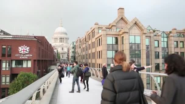 Люди, идущие по мосту Тысячелетия с собором Святого Павла на заднем плане — стоковое видео