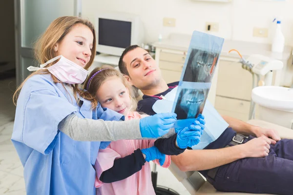 Pequeños dentistas mirando la radiografía de un paciente adulto — Foto de Stock